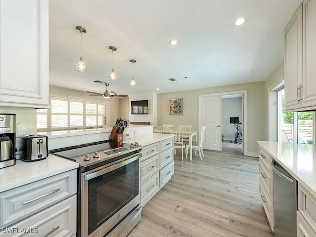 kitchen featuring appliances with stainless steel finishes, pendant lighting, white cabinets, ceiling fan, and light hardwood / wood-style flooring