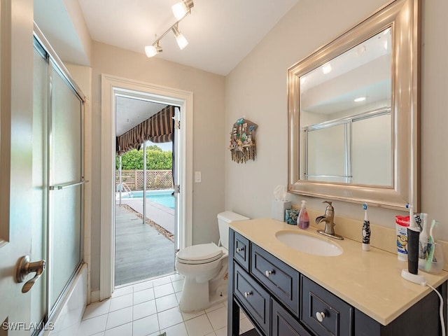 full bathroom featuring rail lighting, shower / bath combination with glass door, tile patterned flooring, vanity, and toilet