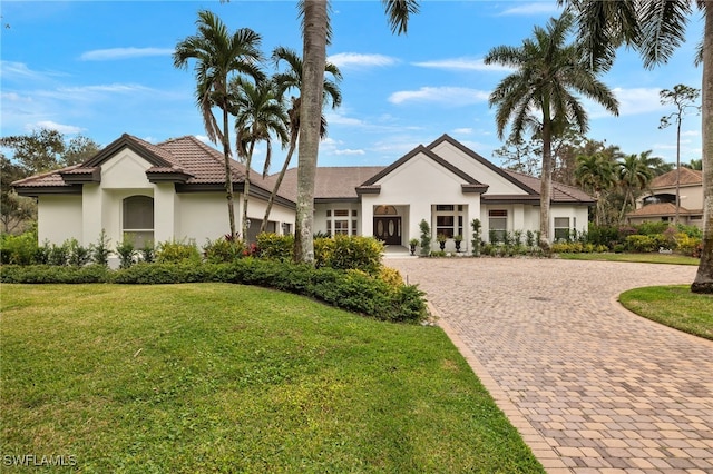 view of front of property featuring a front yard, decorative driveway, and stucco siding