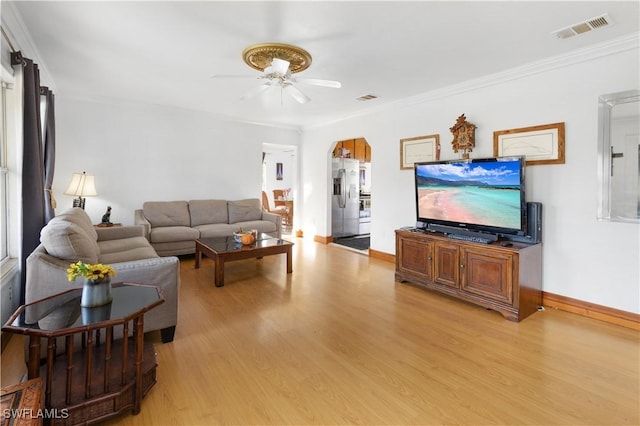 living room featuring ceiling fan, light wood-type flooring, and crown molding