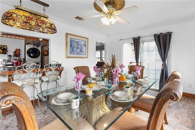 dining room featuring stacked washer / drying machine, ceiling fan, and crown molding