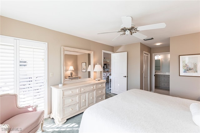 bedroom with ceiling fan, carpet floors, and ensuite bath