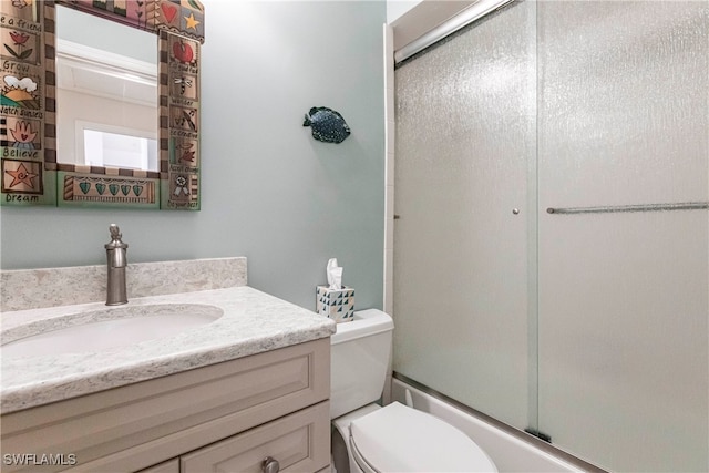 full bathroom with enclosed tub / shower combo, vanity, and toilet