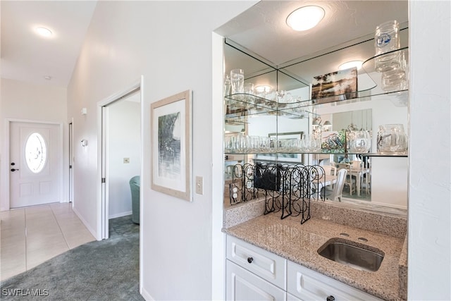 bar with light stone countertops, sink, light carpet, and white cabinets