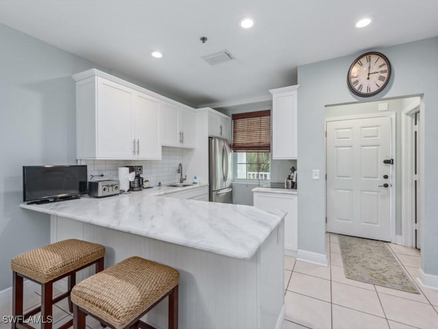 160 Palm St Unit 202, Marco Island, FL 34145 - kitchen featuring freestanding refrigerator, a peninsula, white cabinetry, tasteful backsplash, and a breakfast bar