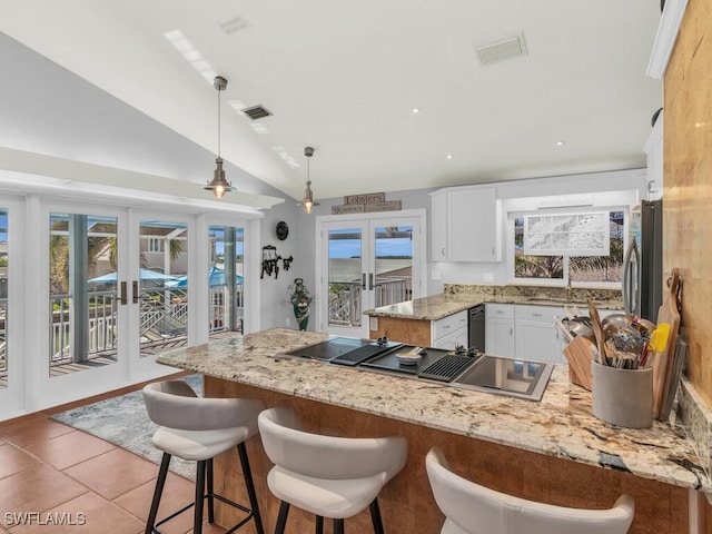 kitchen featuring decorative light fixtures, vaulted ceiling, a wealth of natural light, white cabinetry, and french doors