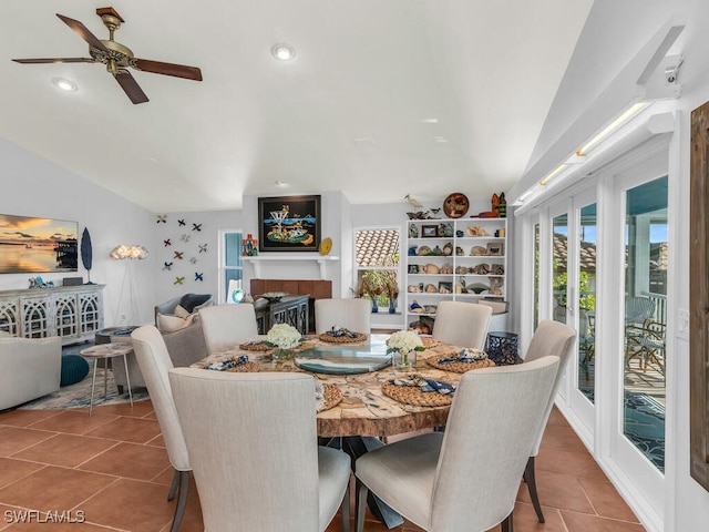 tiled dining room with lofted ceiling, ceiling fan, and a fireplace