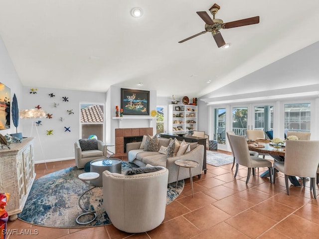 tiled living room with lofted ceiling, ceiling fan, and a tile fireplace