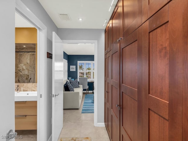 hall featuring light tile patterned floors and sink