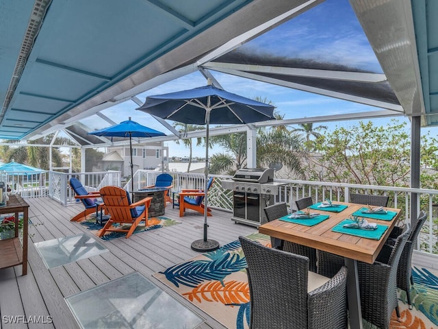 wooden deck featuring glass enclosure and area for grilling