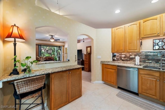 kitchen with sink, ceiling fan, stainless steel dishwasher, and light stone countertops