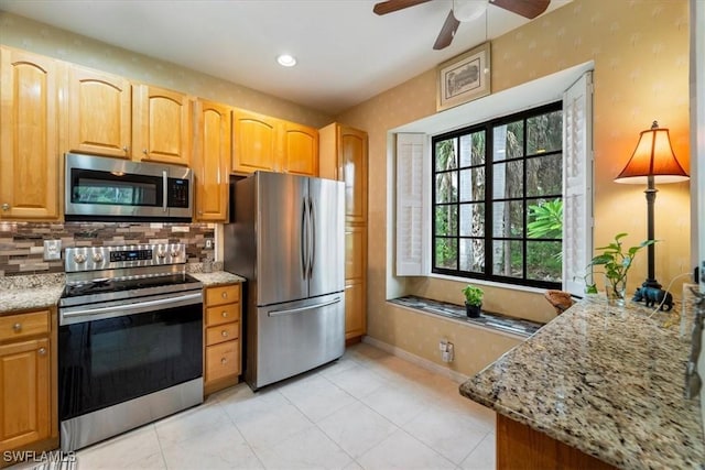 kitchen with stainless steel appliances, light stone counters, light tile patterned flooring, ceiling fan, and backsplash