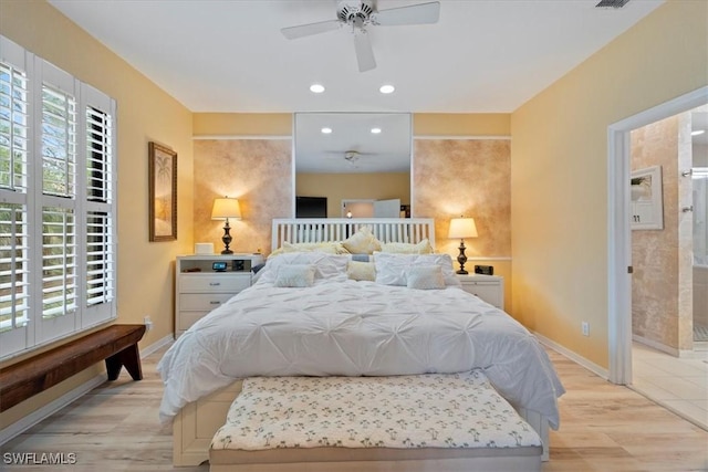 bedroom with ensuite bath, ceiling fan, and light hardwood / wood-style flooring