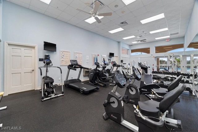 gym with a paneled ceiling, a high ceiling, and ceiling fan