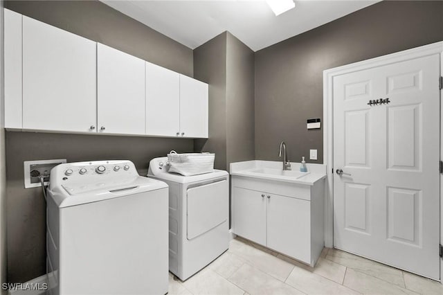 laundry area featuring sink, washing machine and clothes dryer, light tile patterned floors, and cabinets