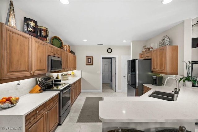 kitchen featuring kitchen peninsula, sink, light tile patterned floors, a breakfast bar area, and stainless steel appliances