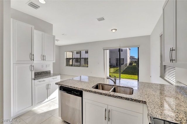 kitchen featuring light stone countertops, stainless steel dishwasher, light tile patterned floors, white cabinets, and sink