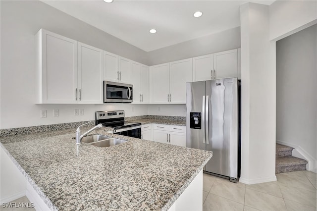 kitchen with light stone countertops, white cabinets, kitchen peninsula, and appliances with stainless steel finishes