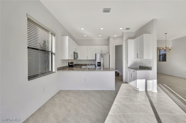 kitchen featuring stainless steel appliances, decorative light fixtures, white cabinetry, kitchen peninsula, and dark stone counters