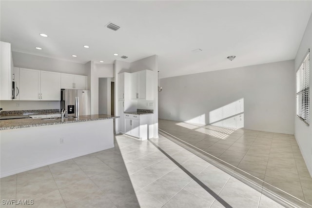 kitchen with sink, white cabinets, light tile patterned flooring, stone countertops, and appliances with stainless steel finishes