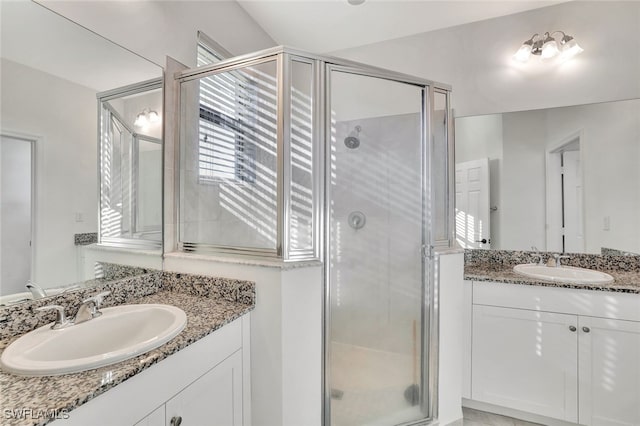 bathroom featuring a shower with shower door and vanity