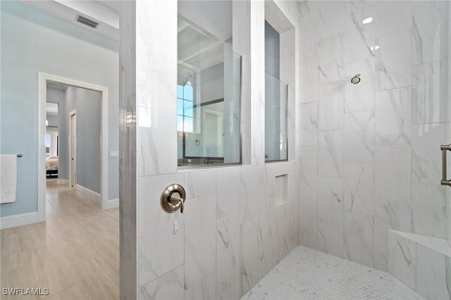 bathroom with wood-type flooring and tiled shower