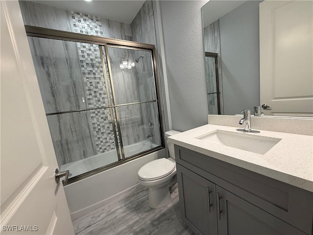 full bathroom featuring shower / bath combination with glass door, vanity, and toilet