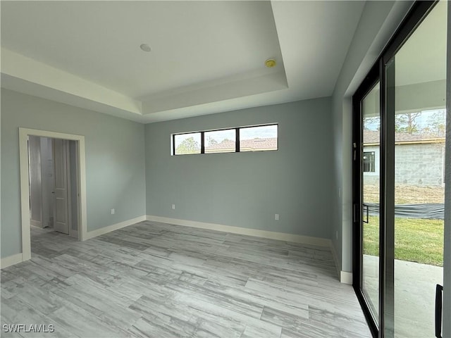 unfurnished room featuring light hardwood / wood-style floors and a raised ceiling