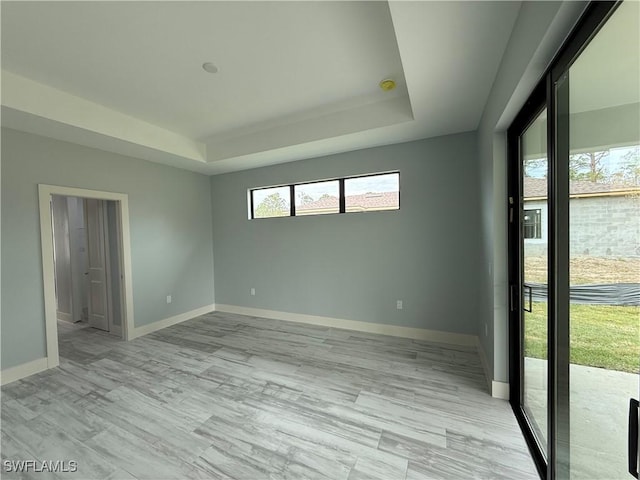 spare room featuring light hardwood / wood-style floors and a tray ceiling