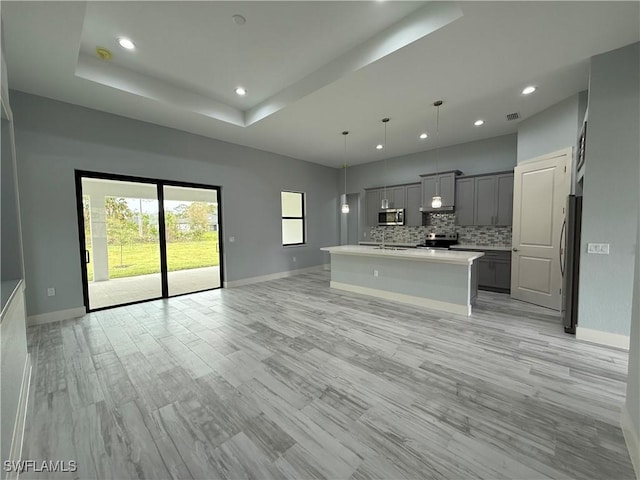 unfurnished living room with light hardwood / wood-style floors and a tray ceiling