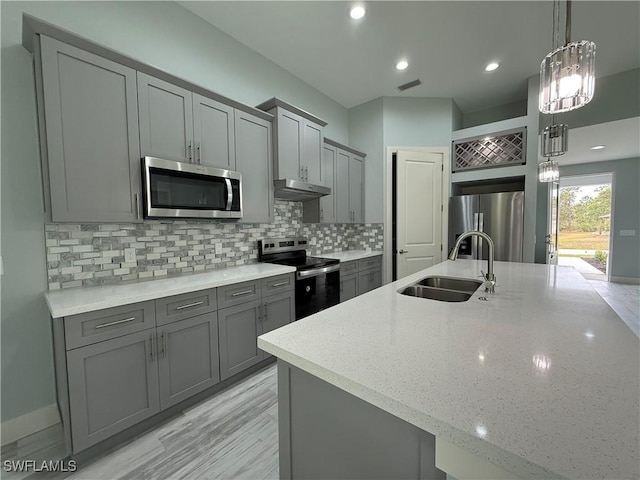 kitchen featuring light stone countertops, pendant lighting, appliances with stainless steel finishes, sink, and backsplash