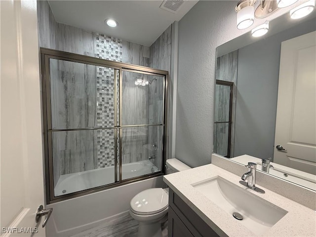 full bathroom with enclosed tub / shower combo, toilet, and vanity