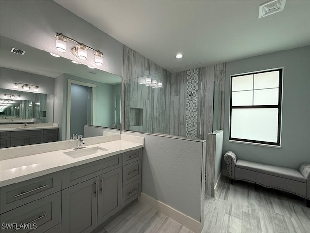 bathroom with vanity, wood-type flooring, plenty of natural light, and a tile shower