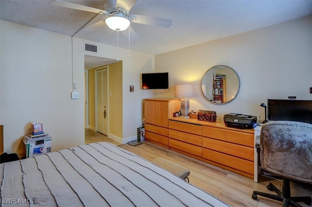 bedroom featuring ceiling fan, a textured ceiling, and light wood-type flooring