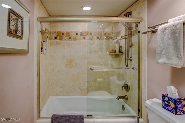 bathroom with toilet and shower / bath combination with glass door