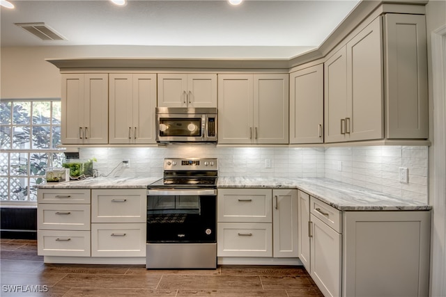 kitchen with light stone countertops, appliances with stainless steel finishes, and tasteful backsplash