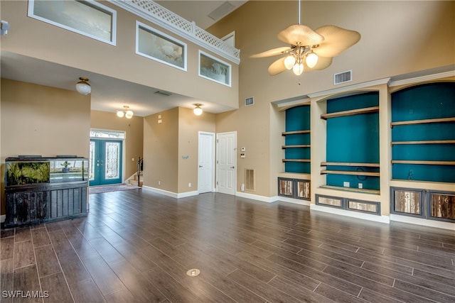 unfurnished living room with ceiling fan, a towering ceiling, built in features, and french doors