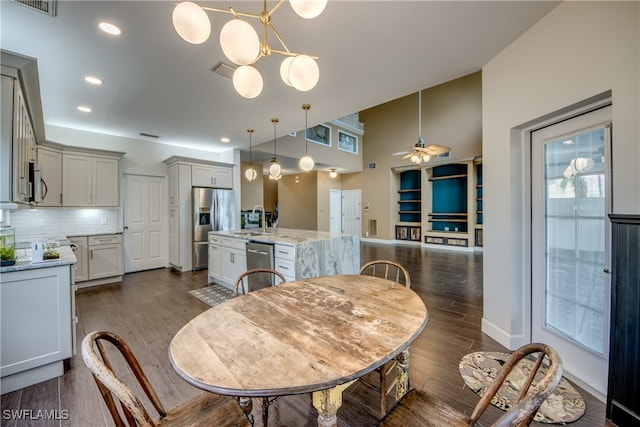 dining space featuring sink, ceiling fan with notable chandelier, and dark wood-type flooring