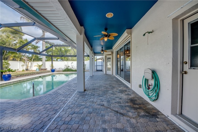 view of swimming pool with glass enclosure, a patio area, and ceiling fan