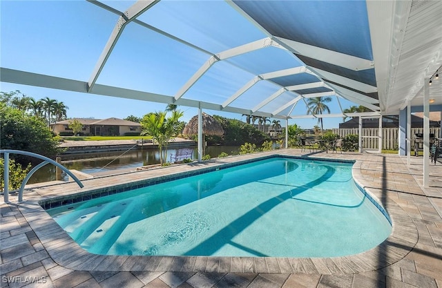 view of swimming pool with a patio area, glass enclosure, and a water view