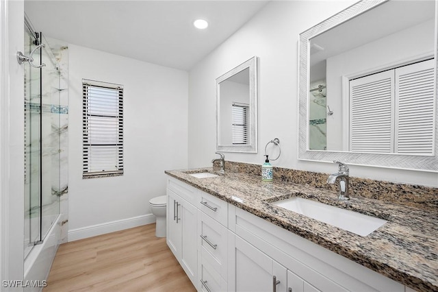 full bathroom with toilet, wood-type flooring, vanity, and combined bath / shower with glass door