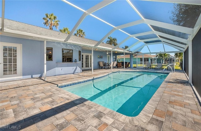 view of pool featuring glass enclosure and a patio area