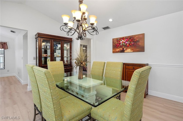 dining space with a notable chandelier, light hardwood / wood-style floors, and lofted ceiling