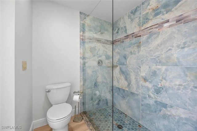 bathroom with a tile shower and toilet