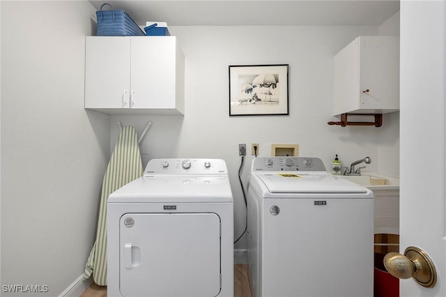 clothes washing area featuring separate washer and dryer and cabinets