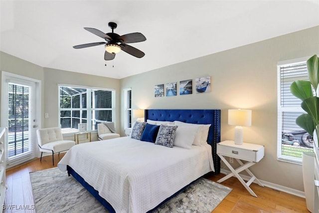 bedroom featuring ceiling fan, light hardwood / wood-style flooring, access to outside, and multiple windows