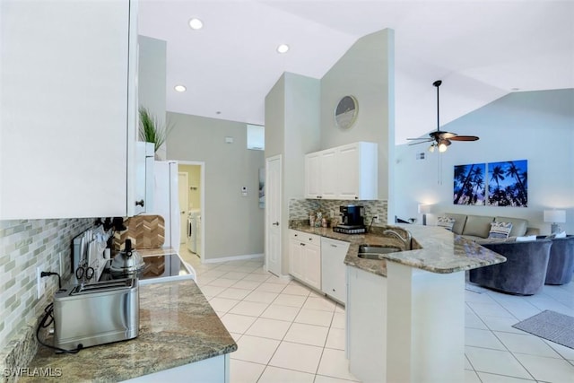 kitchen with kitchen peninsula, stone countertops, and white cabinetry