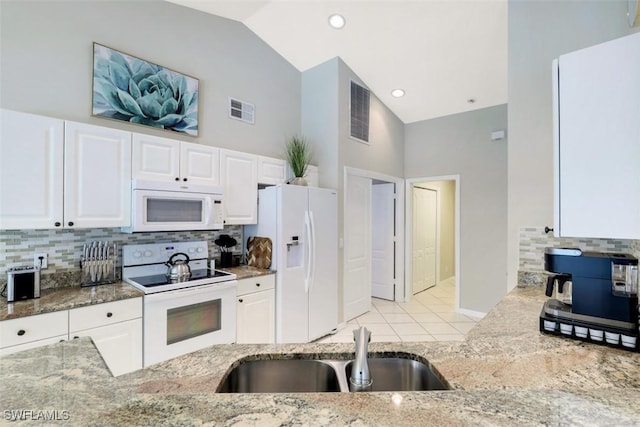 kitchen featuring white appliances, white cabinets, and light stone counters