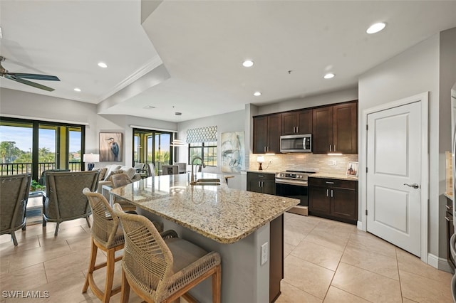 kitchen featuring stainless steel appliances, sink, a kitchen breakfast bar, ceiling fan, and an island with sink