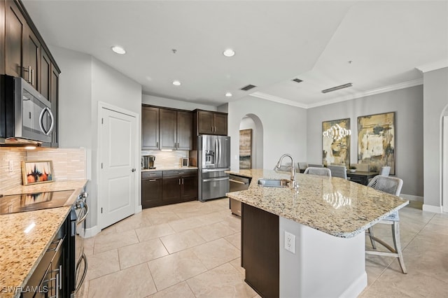 kitchen with stainless steel appliances, sink, a kitchen island with sink, tasteful backsplash, and a breakfast bar